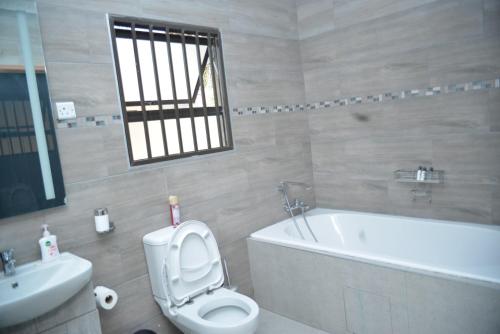 a bathroom with a toilet and a tub and a sink at Kebo events agro &self catering apartments in Mochudi