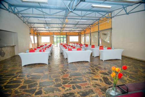 a large room with white tables and red chairs at Kebo events agro &self catering apartments in Mochudi
