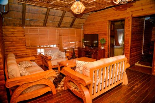 a living room with couches and a tv in a log cabin at Kebo events agro &self catering apartments in Mochudi