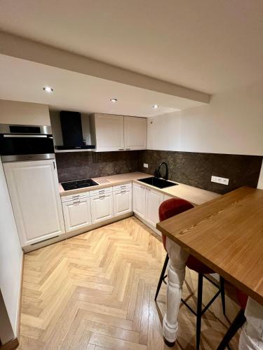 une cuisine avec des armoires blanches et une table en bois dans l'établissement Appartement Bourg Saint Maurice, à Bourg-Saint-Maurice