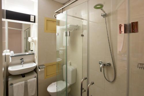 a bathroom with a shower and a toilet and a sink at Hotel Expo in Brussels