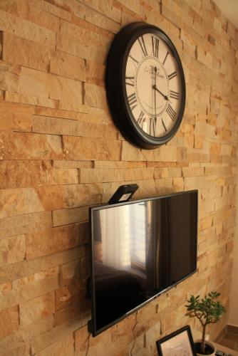 a clock hanging on a brick wall with a tv at Silvani Kop NLux67, Milmari Apartments & Spa in Kopaonik