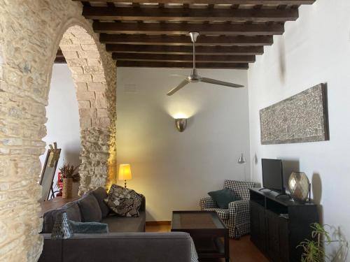 a living room with a couch and a ceiling fan at Arcos de la Loba by casitasconencantoes in Medina Sidonia
