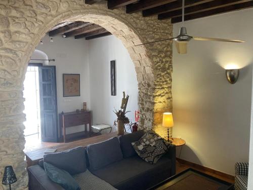 a living room with a blue couch and a stone wall at Arcos de la Loba by casitasconencantoes in Medina Sidonia