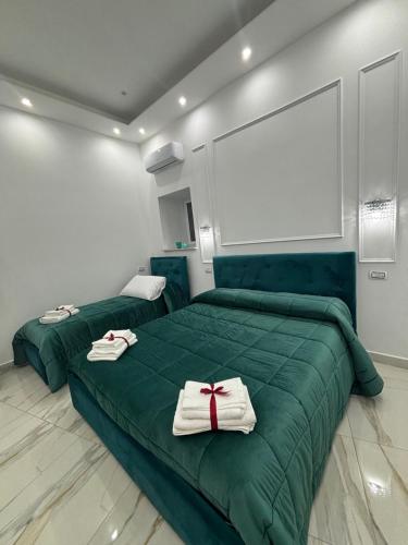 een slaapkamer met twee groene bedden met handdoeken erop bij Marghe Luxury Home in Napels