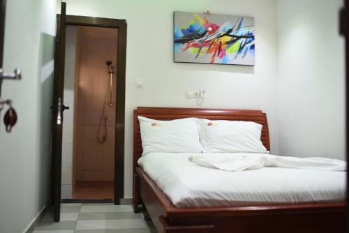a bedroom with a bed with white sheets at Résidence Le Sommet Douala in Douala