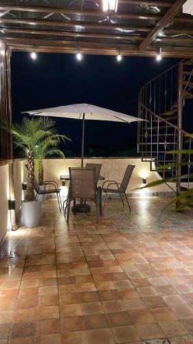 a patio with chairs and a table and an umbrella at Casa grande de lujo cerca Antigua Guatemala in Antigua Guatemala
