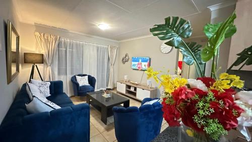 a living room with blue couches and a table and flowers at Nyasa Apartment in Johannesburg