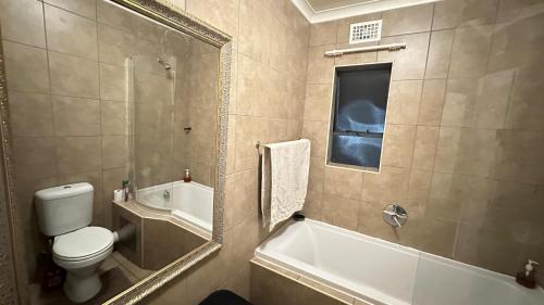a bathroom with a toilet and a tub and a sink at Nyasa Apartment in Johannesburg