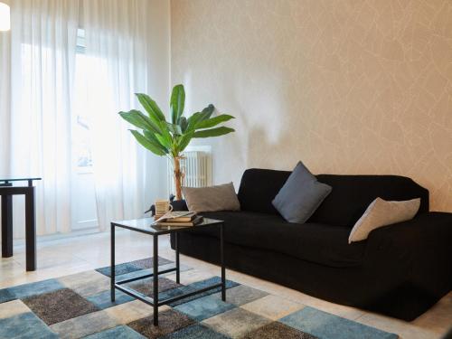 a living room with a black couch and a potted plant at Ca' De Amicis - Ampio bilocale con parcheggio privato in Rho