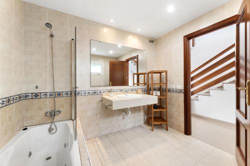 ein Badezimmer mit Badewanne, Waschbecken und Spiegel in der Unterkunft La casa de la playa in Playa Honda