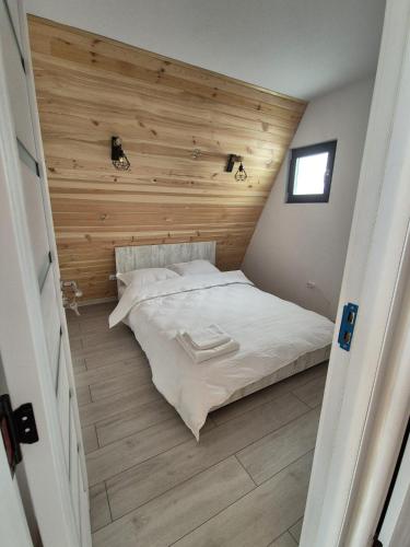 a bed in a room with a wooden wall at A-frame Muchia Scortii in Şimon