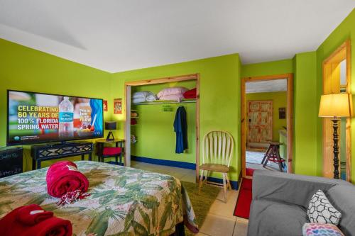 a bedroom with green walls and a bed and a tv at Blue Bell Apartment Hotel in Fort Lauderdale