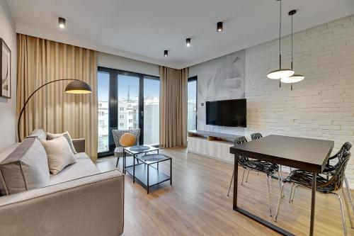 een woonkamer met een bank en een tafel bij Montevideo Centrum 15 by Grand Apartments in Sopot