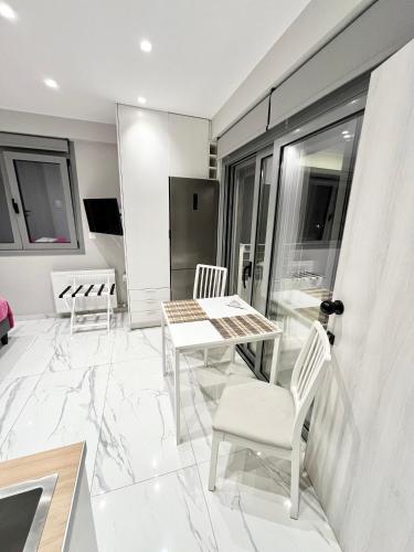 a white living room with a table and chairs at BlueLine apartment 2 in Loutraki
