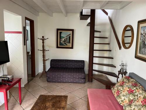 a living room with a couch and a spiral staircase at Casinhas do Peró Refúgio com Jardim e WiFi Rápido in Cabo Frio