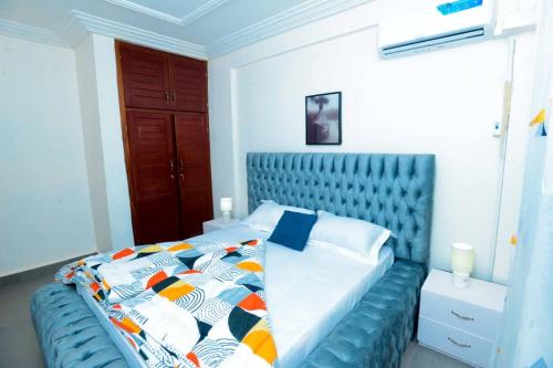 a bed with a blue headboard in a bedroom at Résidence Le Prestige in Yaoundé