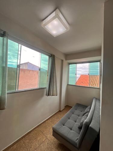 a living room with a couch and two windows at Estalagem pé na areia in Arraial do Cabo