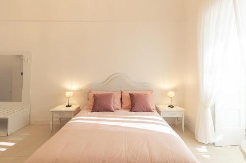 a white bedroom with a large bed with pink pillows at Dimora Margherita in Caserta