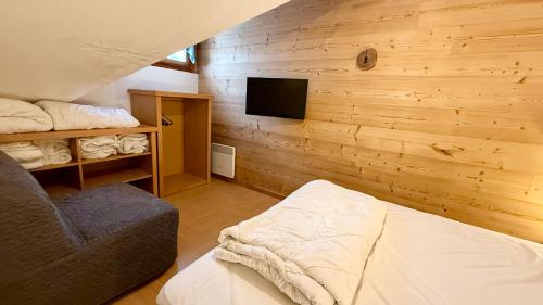 - une chambre avec un mur en bois, un lit et une télévision dans l'établissement Appartement aux Orres 1800, aux Orres
