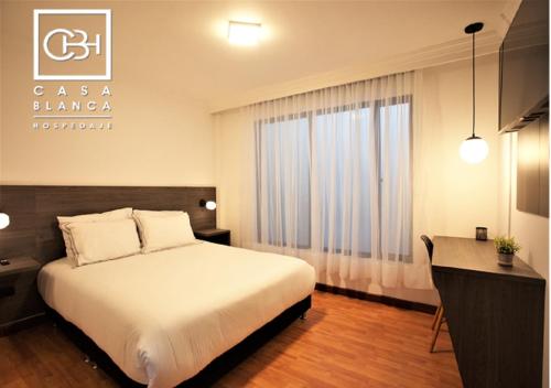 a bedroom with a bed and a desk and a window at Casa Blanca Hospedaje Pasto SAS in Pasto