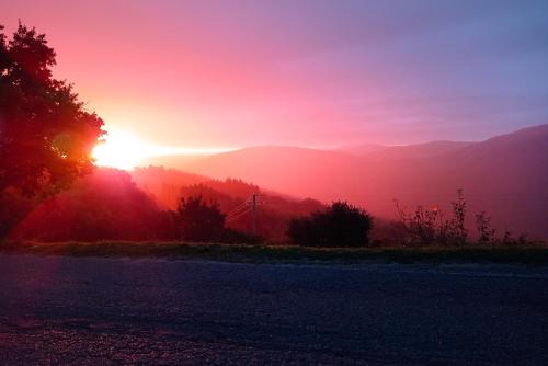 a sunset on a hill with a road and mountains at Agriturismo la Coccinella in Poggioni