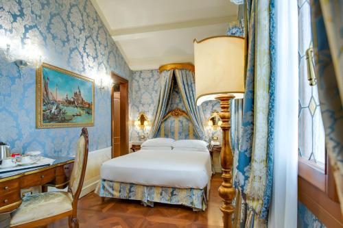 a bedroom with blue wallpaper with a bed and a desk at Canal Grande in Venice