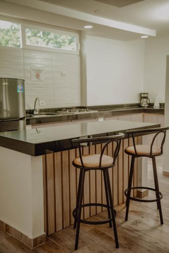 a kitchen with two bar stools at a counter at Deluxe in Valledupar