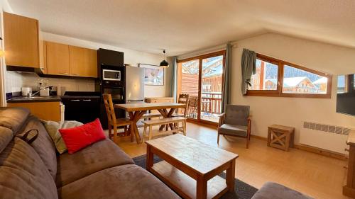 un salon avec un canapé et une cuisine avec une table dans l'établissement Appartement aux Orres 1800, aux Orres