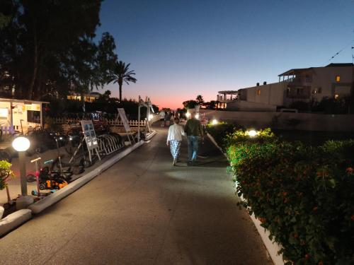 two people walking down a sidewalk at night at Relaxrooms, room with 2 single beds in Agios Georgios