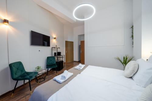 a bedroom with a large white bed and two chairs at Hama Boutique Stays in Budapest
