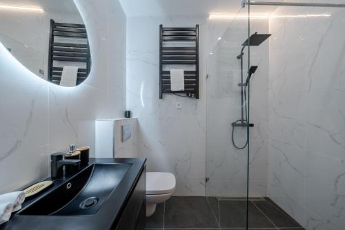 a bathroom with a sink and a toilet and a mirror at Hama Boutique Stays in Budapest