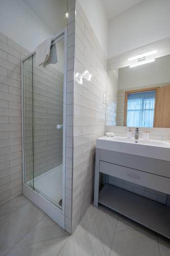 a bathroom with a glass shower and a sink at Hama Boutique Stays in Budapest