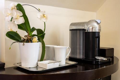 a table with a coffee maker and flowers on it at Hummingbird Haven Bed & Breakfast Luxury Suite With Terrace & Seasonal Lake Views Located in Historic Old Town Niagara-On-The-Lake in Niagara-on-the-Lake