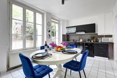 une cuisine avec une table blanche et des chaises bleues dans l'établissement Le Bellanger - Duplex tout équipé proche Paris, à Levallois-Perret