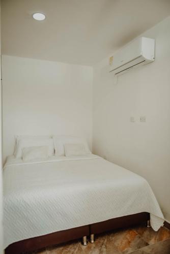 a white bed in a room with a white wall at Comfort in Valledupar
