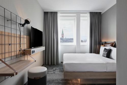 a hotel room with a bed and a window at Moxy Duesseldorf City in Düsseldorf