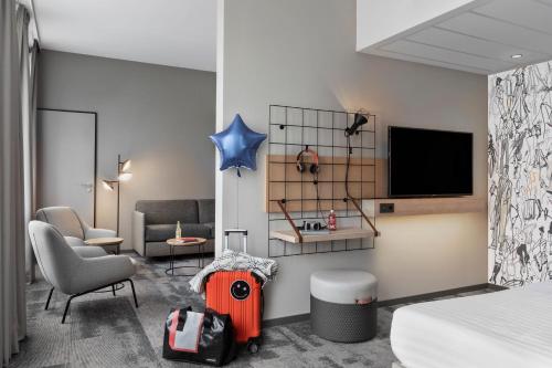 a room with a bed a chair and a television at Moxy Duesseldorf City in Düsseldorf