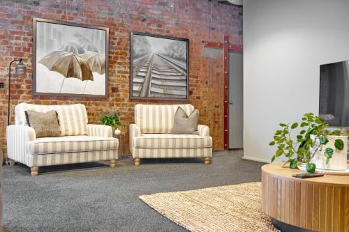 a living room with two chairs and a brick wall at The Loft on Cuba in Wellington