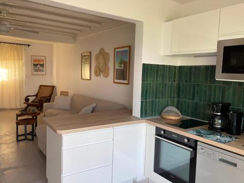 a kitchen with white cabinets and a living room at Ans'O - Les Anses d'Arlet in Les Anses-dʼArlets