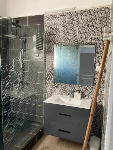a bathroom with a sink and a shower with a mirror at Ans'O - Les Anses d'Arlet in Les Anses-dʼArlets