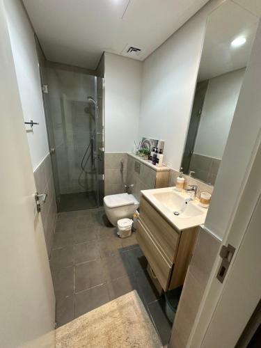 a bathroom with a toilet and a sink and a shower at Cozy Golf & Lake View 1BR Apartment,Damac Hills 1 in Dubai