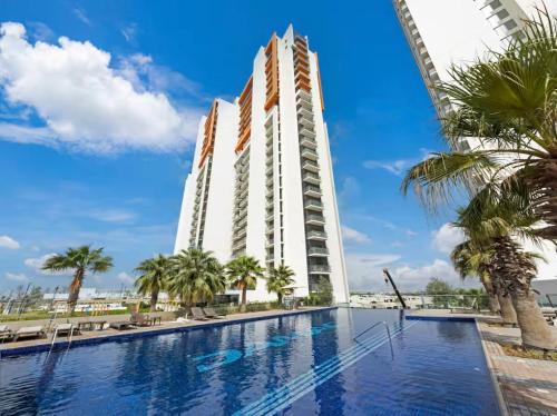 a hotel with a swimming pool and palm trees at Cozy Golf & Lake View 1BR Apartment,Damac Hills 1 in Dubai