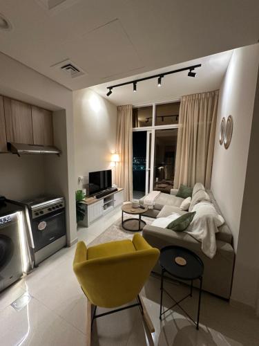 a living room with a couch and a yellow chair at Cozy Golf & Lake View 1BR Apartment,Damac Hills 1 in Dubai