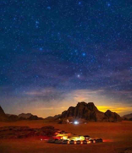 a group of cars parked in the desert under a star filled sky at Wadi Rum Travel camp in Wadi Rum