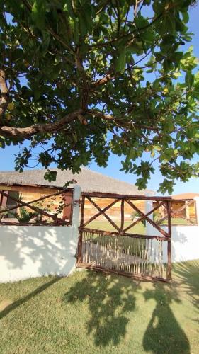 a wooden gate in front of a building with a tree at Chalés Passagem do Canto in Barreirinhas