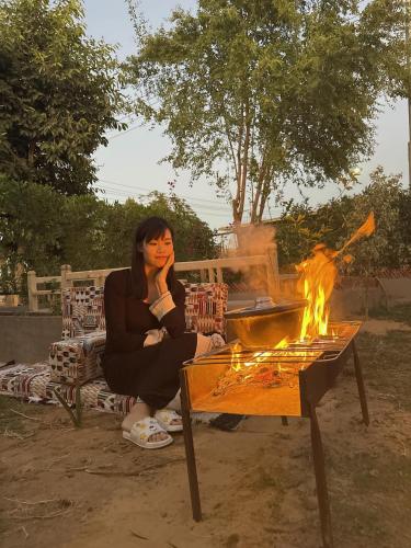 a woman sitting on a bench next to a fire at Karma Kono in Abu Simbel