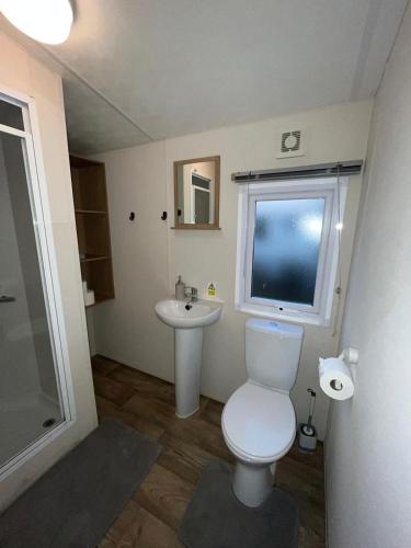 a bathroom with a toilet and a sink and a window at The Getaway Billing Aquadrome in Great Billing
