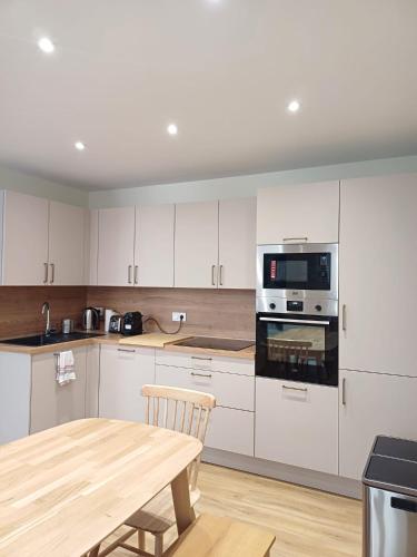 une cuisine avec des armoires blanches et une table en bois dans l'établissement maison quartier préfecture 4 chambres 3 sdb wifi, à Agen
