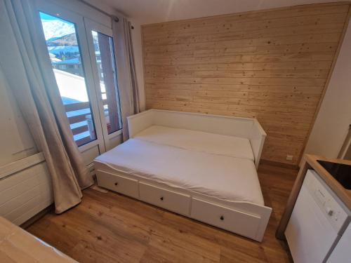 un petit lit dans une chambre avec une fenêtre dans l'établissement Centre Station - La Vallée Blanche 2 - La Foux, à Allos